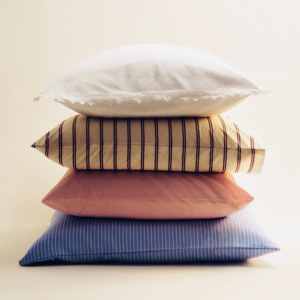 Stack of four pillows with different patterns and colors on a light background