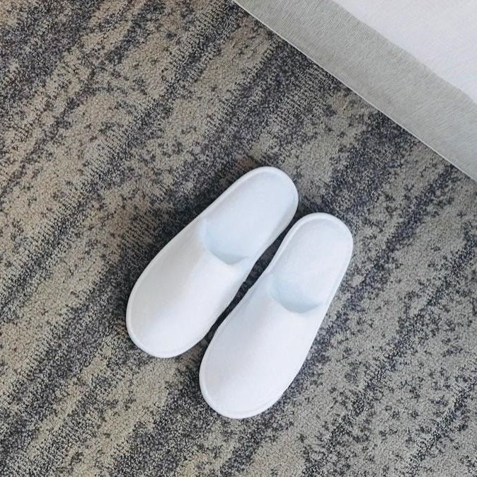 Pair of white slippers on a textured gray floor